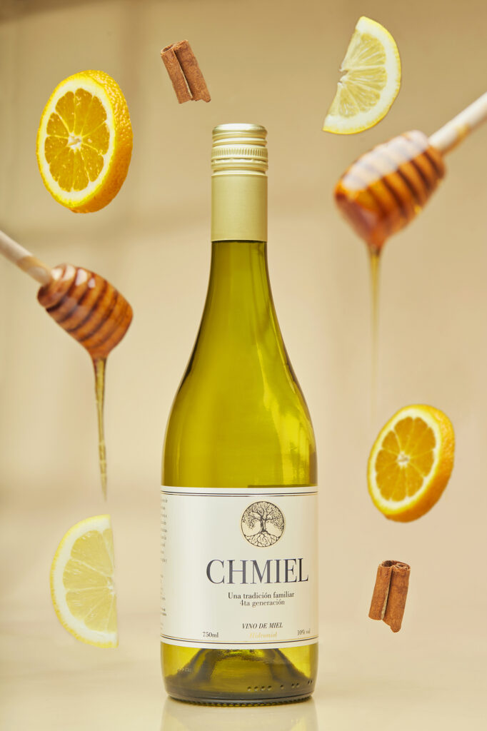 Fotografía de producto con elementos en suspensión que realzan el vino de miel, por RUMA Estudio, Uruguay.